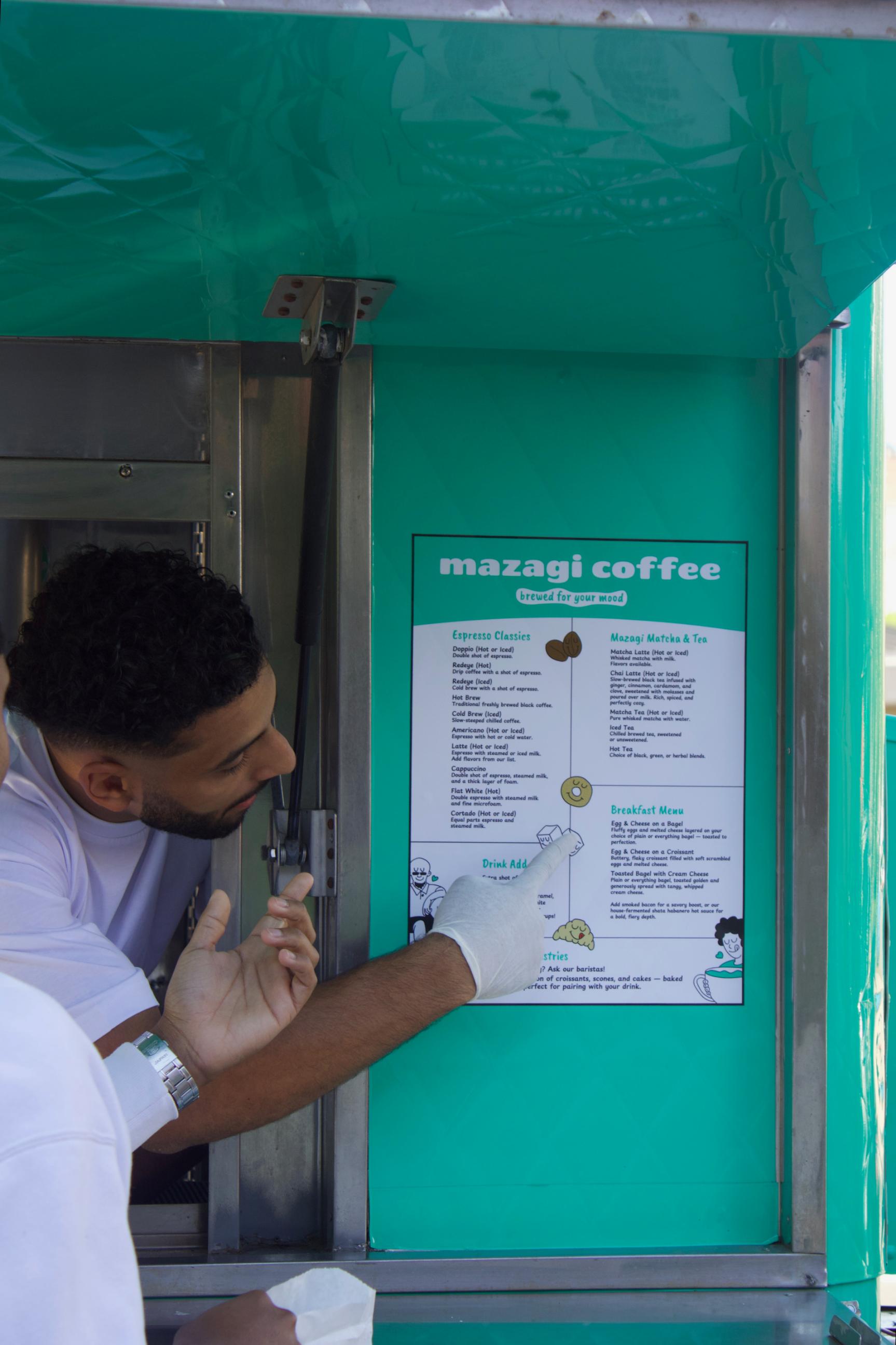 Mazagi barista pointing at the posted drink menu